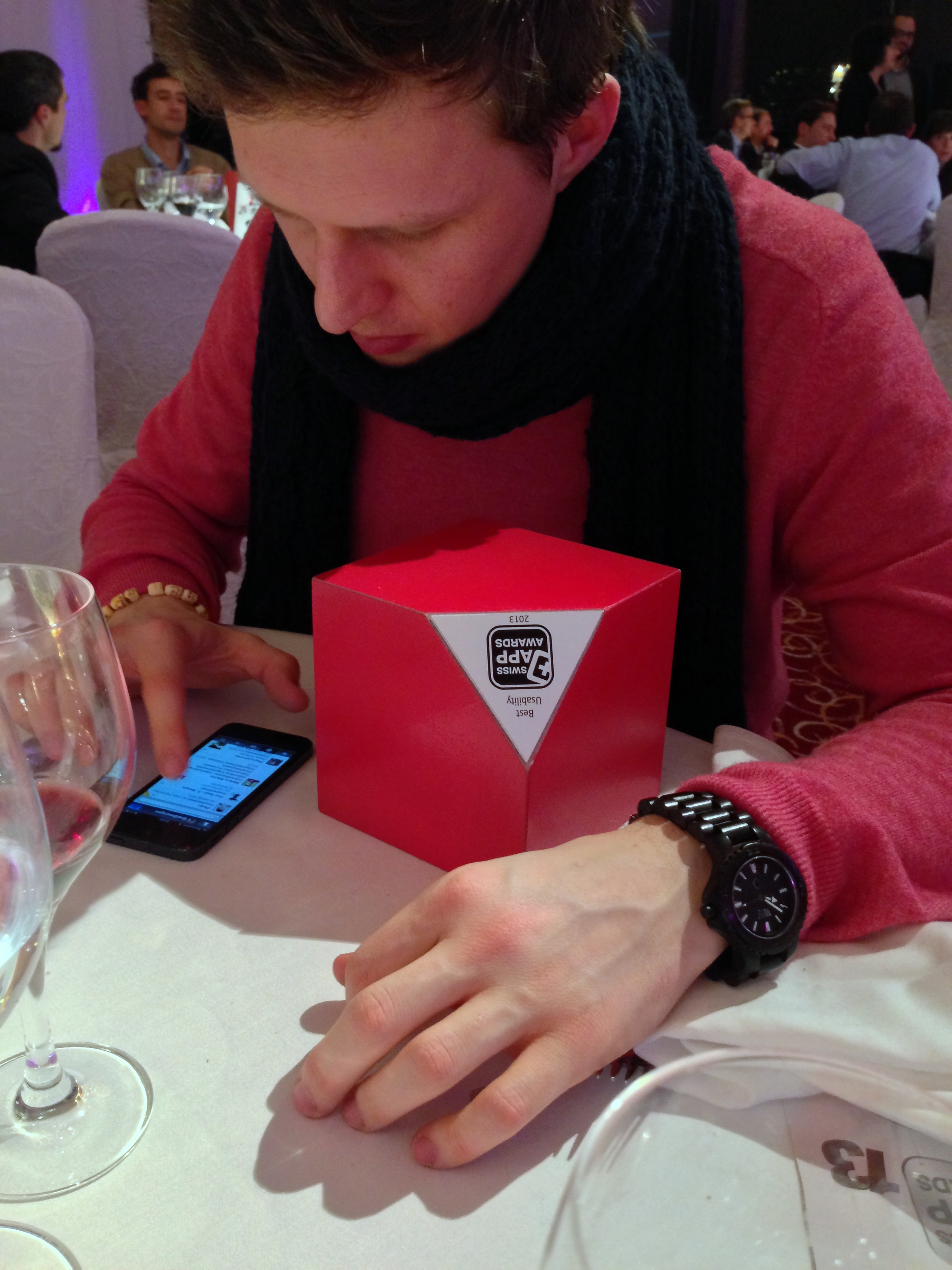 Till mit dem Award für Best Usability, sitzt am Tisch und tippt auf dem iPhone