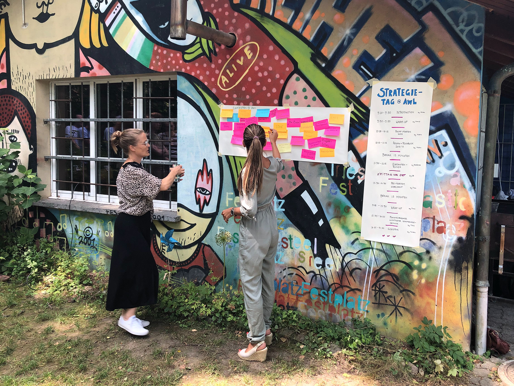 Fabienne und Sonia kleben Post its auf eine besprayte Wand