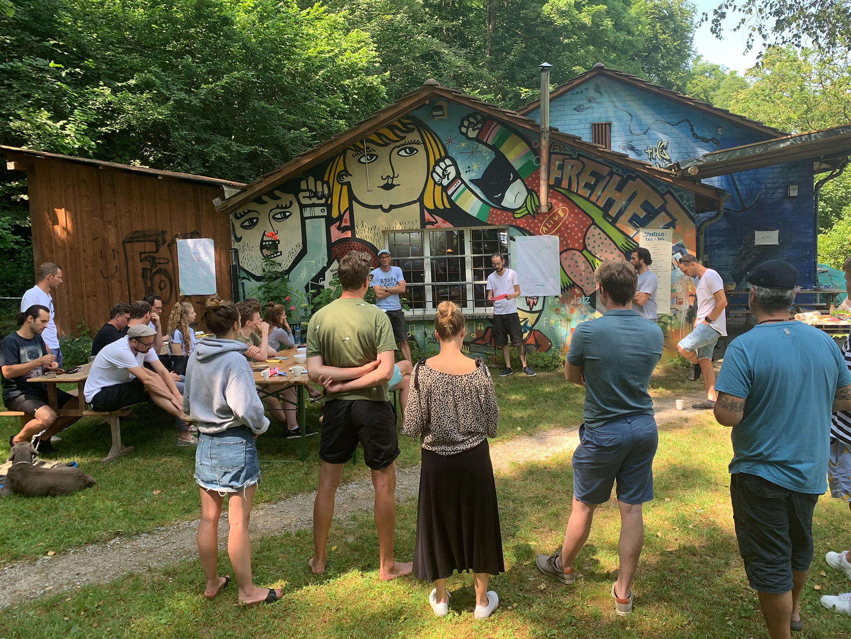 Apps with love Mitarbeitende stehen draussen im Kreis und hören zu wie Valentin etwas erzählt