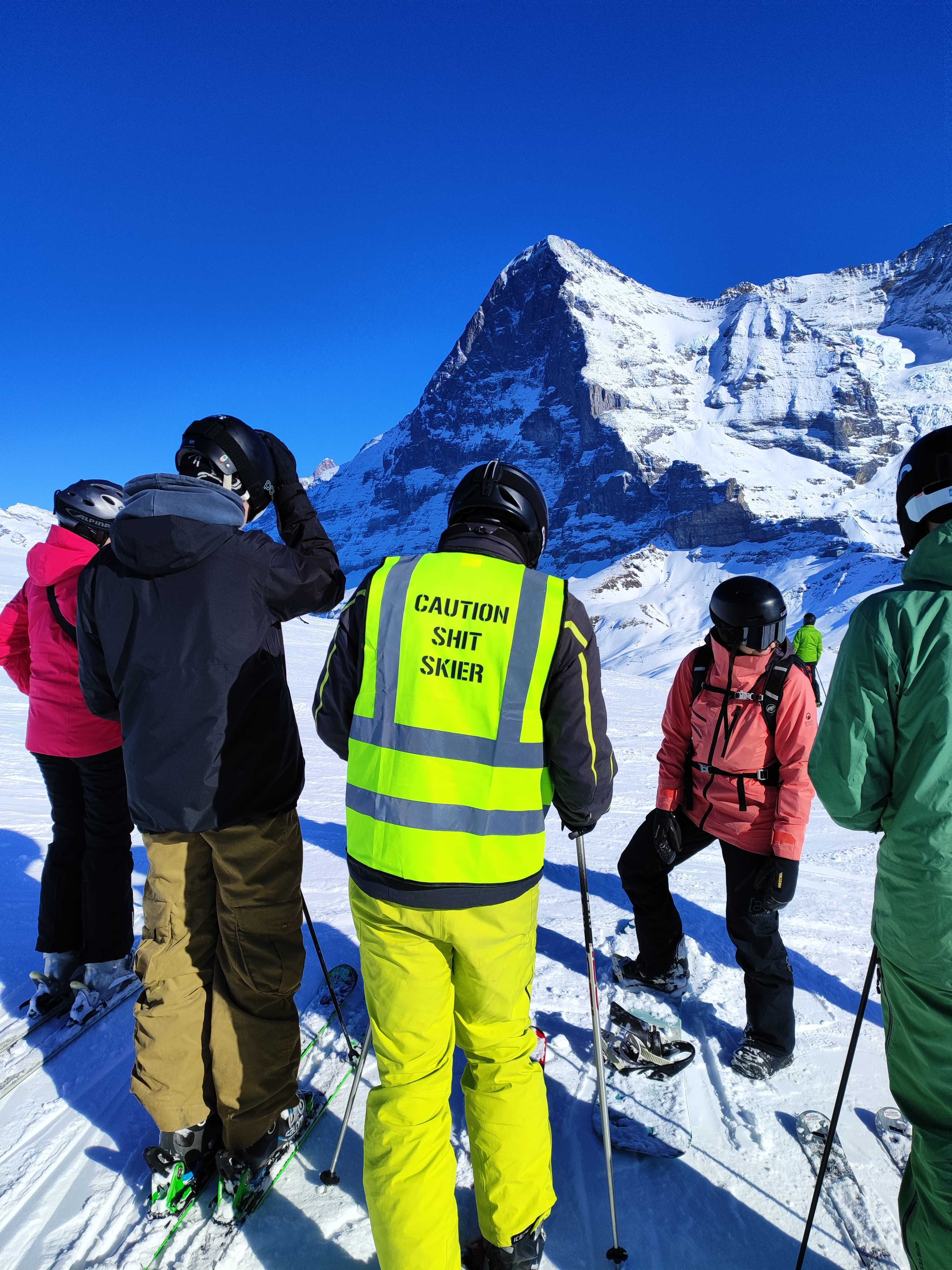 Skifahrer mit Leuchtweste mit Aufschrift