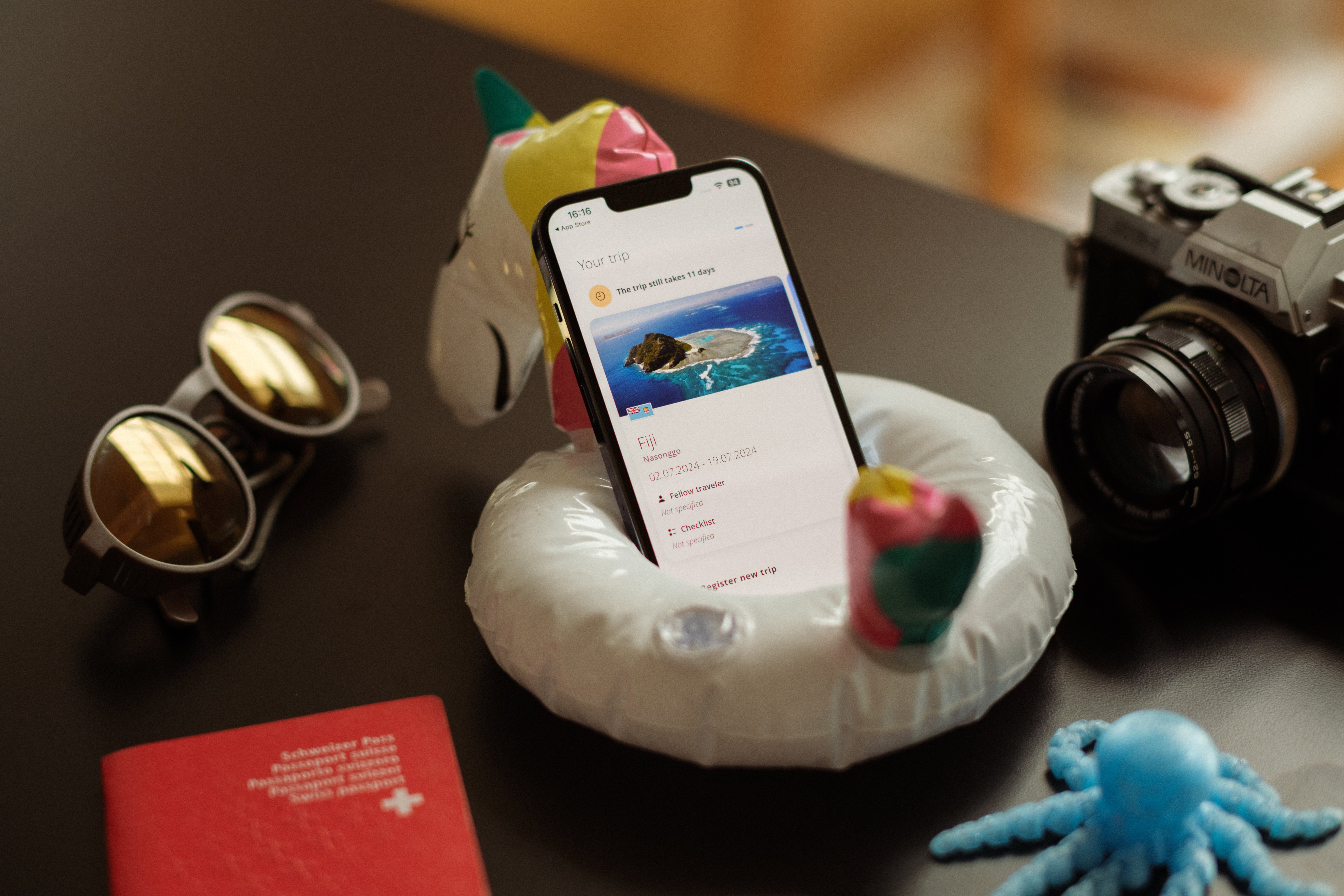 Die Travel Admin App des EDA geöffnet auf einem iPhone, das in einem aufblasbaren kleinen Schwimmring platziert ist