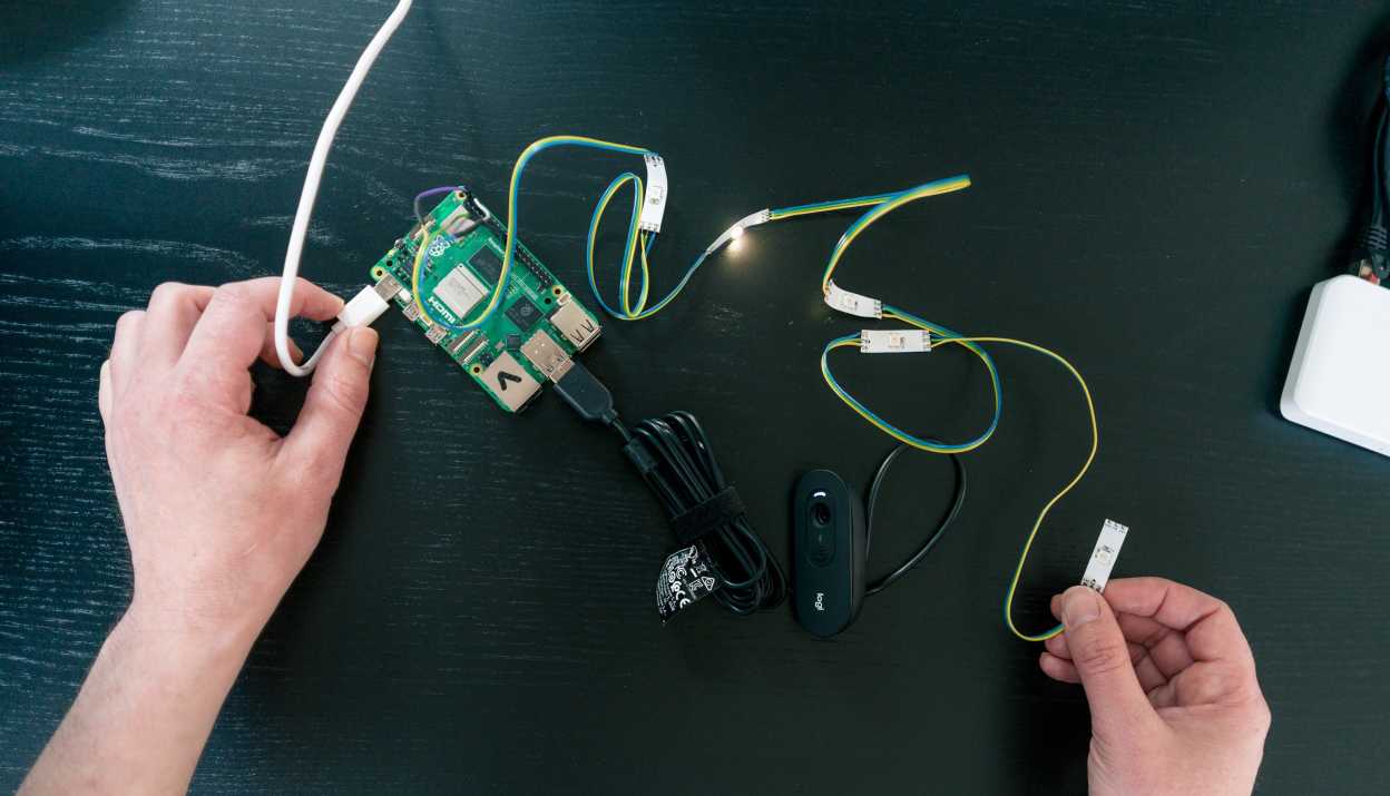 Zwei Hände, welche mit Kabel und Elektronik hantieren, um Komponenten und Sensoren zu installieren
