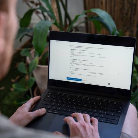 Eine Person von hinten über die Schulter fotografiert, die an einem Laptop arbeitet und die Co-Pilot-Benutzeroberfläche geöffnet hat.