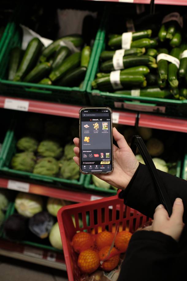 Person buying vegetables according to their Denner Shopping List