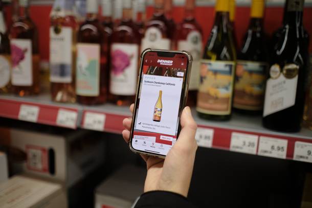 Handy mit geöffnetem Weinscanner vor Weinregal