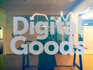Schriftzug "Digital Goods" fotografiert vor einem farbig spiegelnden Fenster