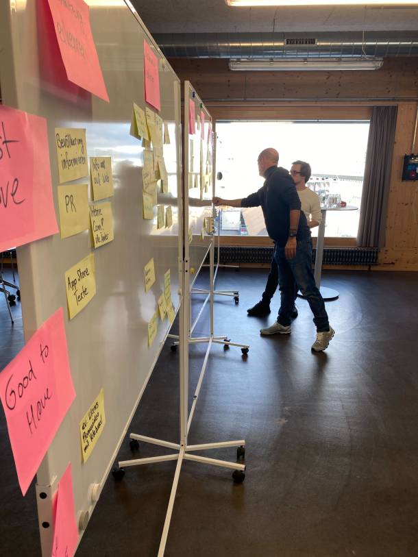 Two people discuss ideas on post-its in front of a whiteboard