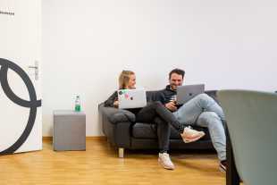 Fabienne und Martin mit Laptops auf dem Sofa