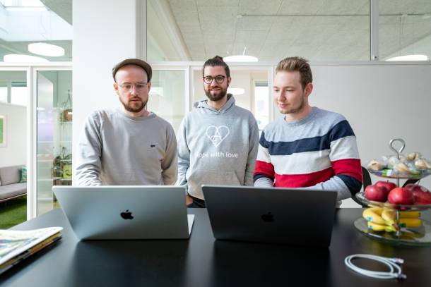 Stefan, Matt und Alain bei einer Besprechung vor zwei Laptops