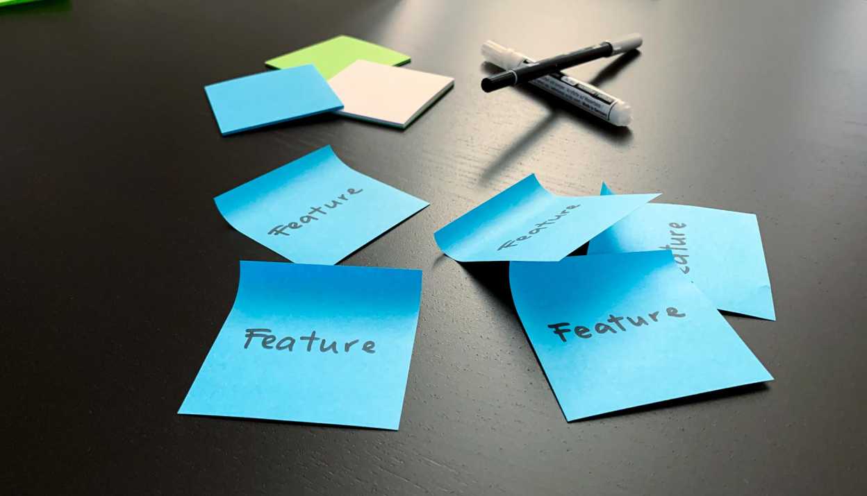Blue post-its with "Feature" written on them are stuck on a table